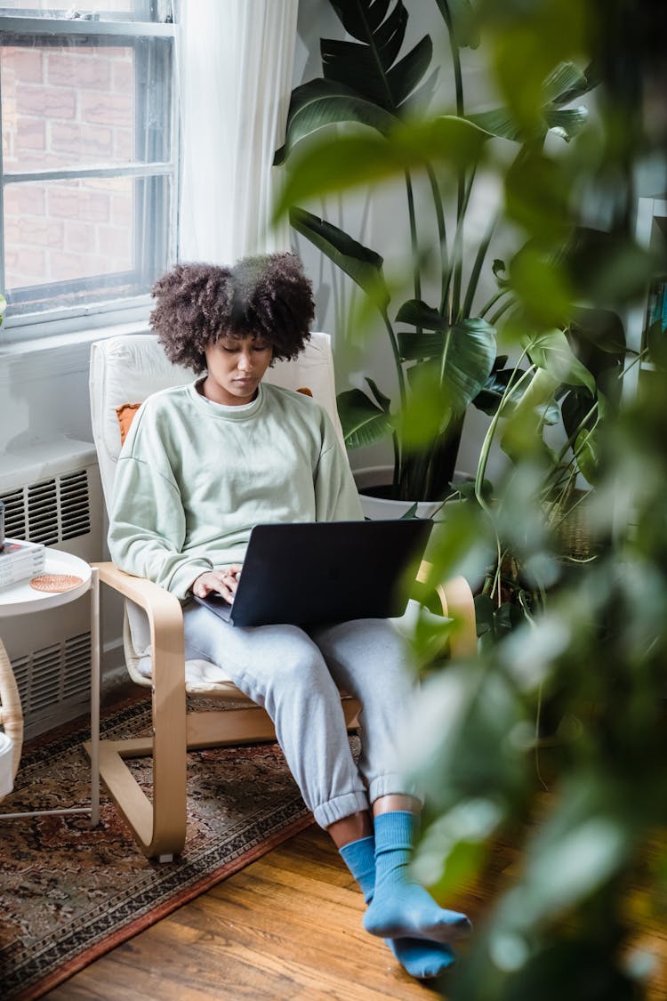 Woman Relaxing At Chair At Home With Laptop