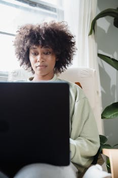 African American woman working on laptop in cozy home setting.