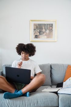Woman focused on remote work with laptop while sitting on sofa.