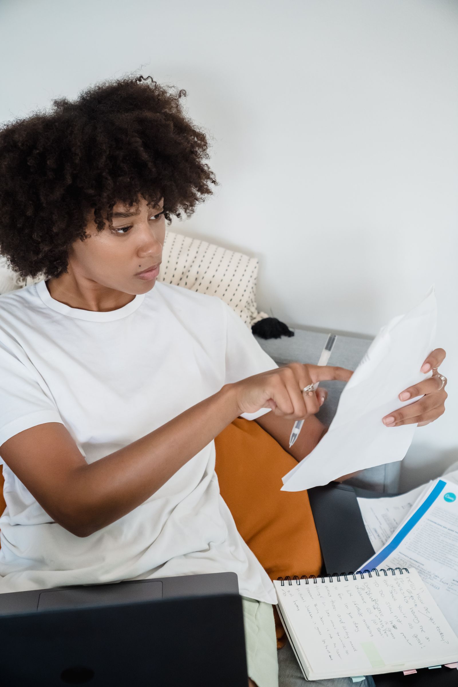 Professionnelle examinant des documents à côté d’un ordinateur portable
