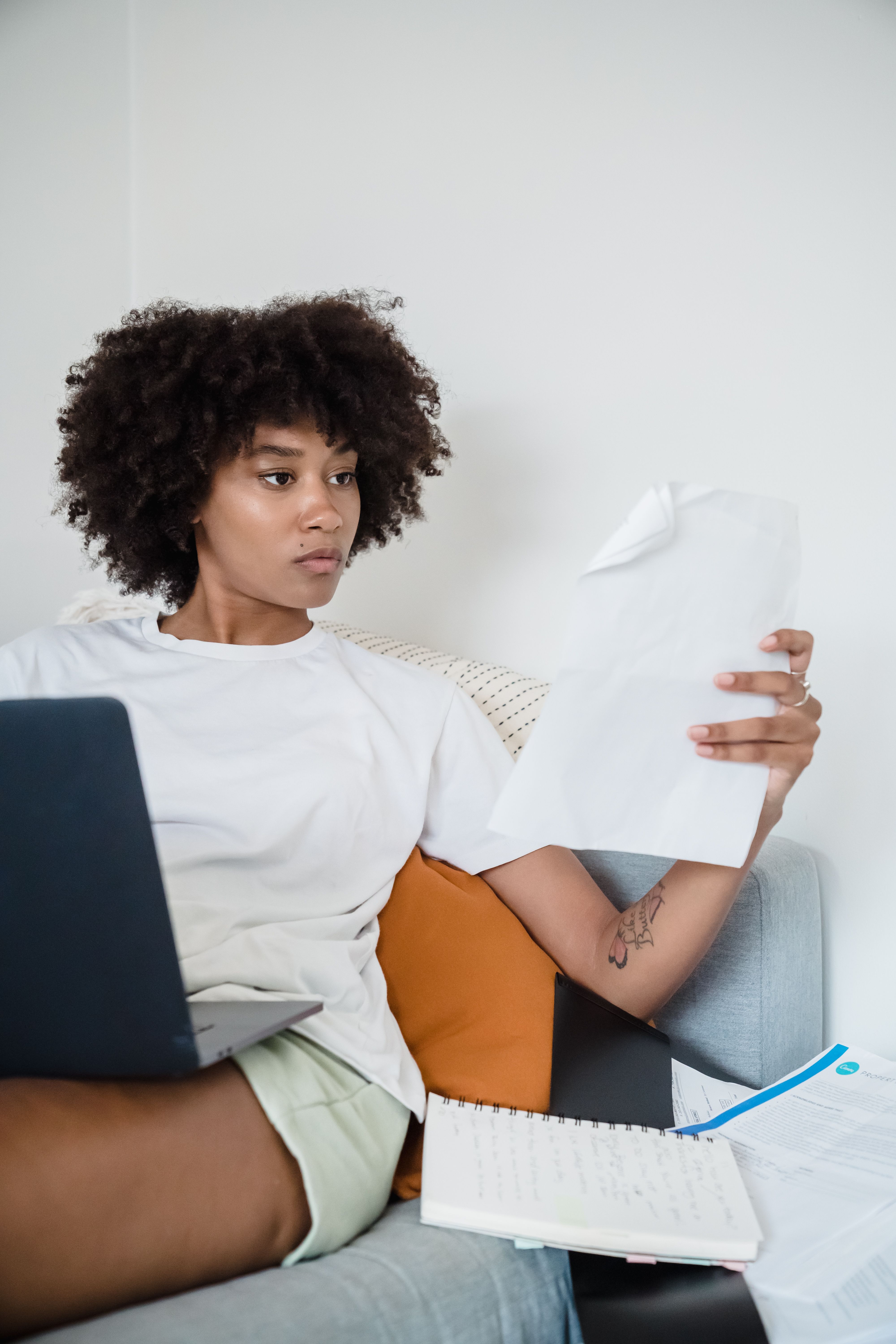 Woman reviewing paper documents beside a laptop at home