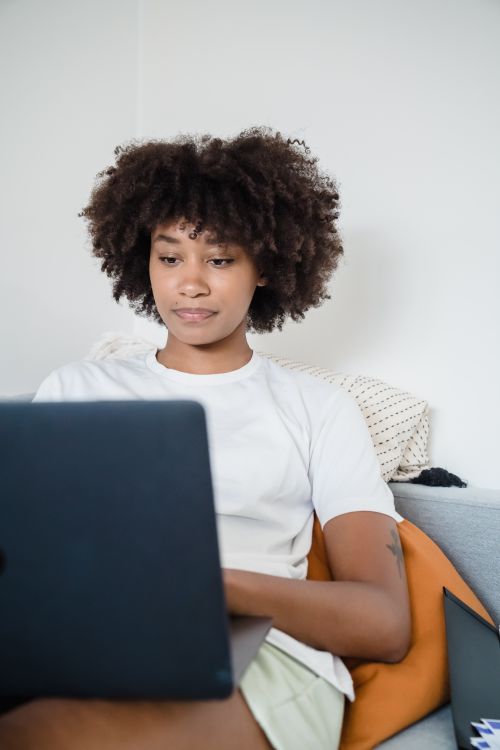Free Casual home workspace featuring a young woman focusing on remote work using a laptop. Stock Photo