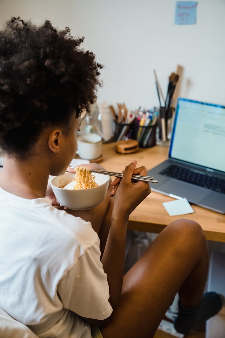 Woman Eating Noodles At Home Office