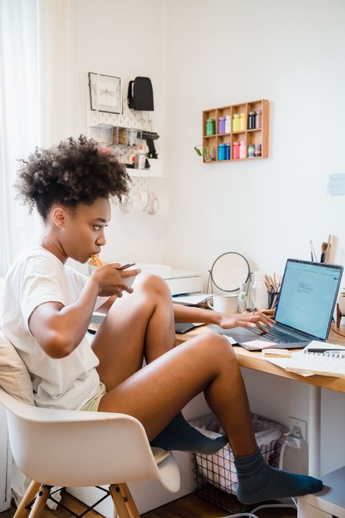 Free Young woman multitasking with remote work and lunch at home office. Stock Photo