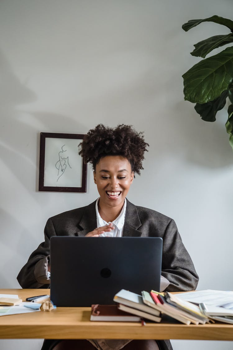 Businesswoman Sitting At Desk Talking On Webcam On Laptop