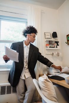 Confident businesswoman printing documents at home office desk.