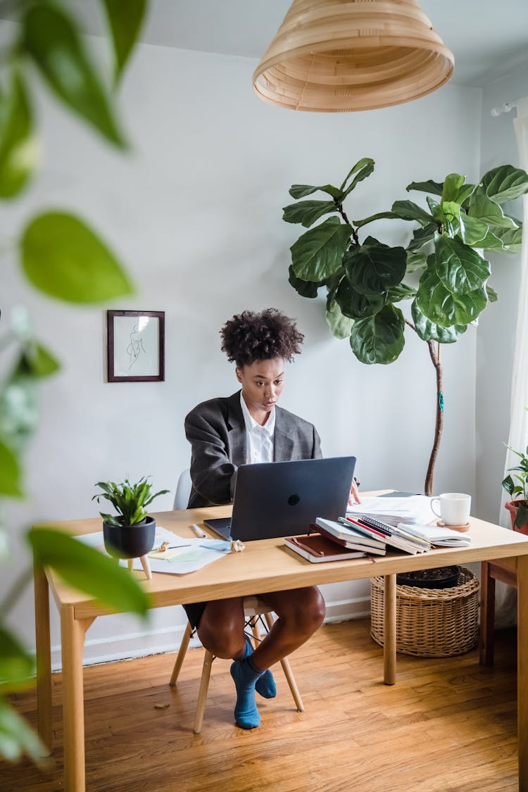 Woman In Suit Sitting At Table Working On Laptop