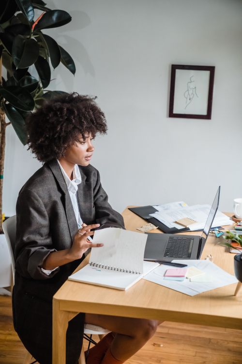 Free Businesswoman working at a desk with a laptop and notes inside an office. Stock Photo