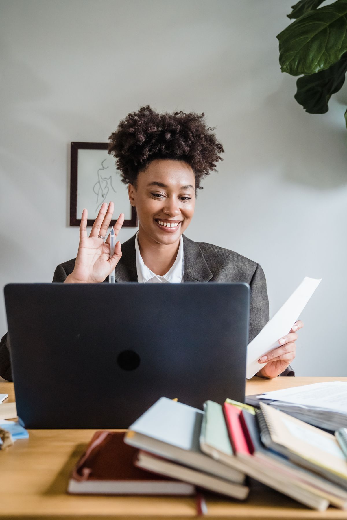 A woman waving during a business video call on a laptop