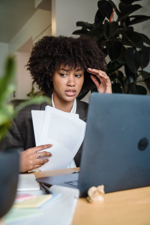 Free Focused woman feeling stressed while working with laptop and documents at her desk. Stock Photo