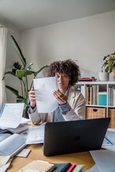 Woman working remotely with documents, focusing on office tasks at a desk.
