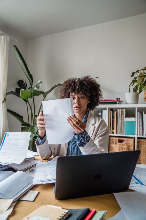 Free Woman working remotely with documents, focusing on office tasks at a desk. Stock Photo