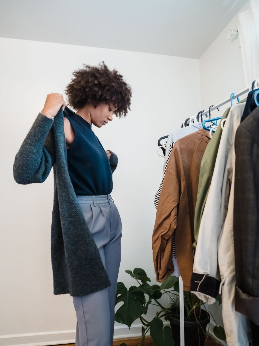 A woman selecting a coat from a wardrobe rail in natural light