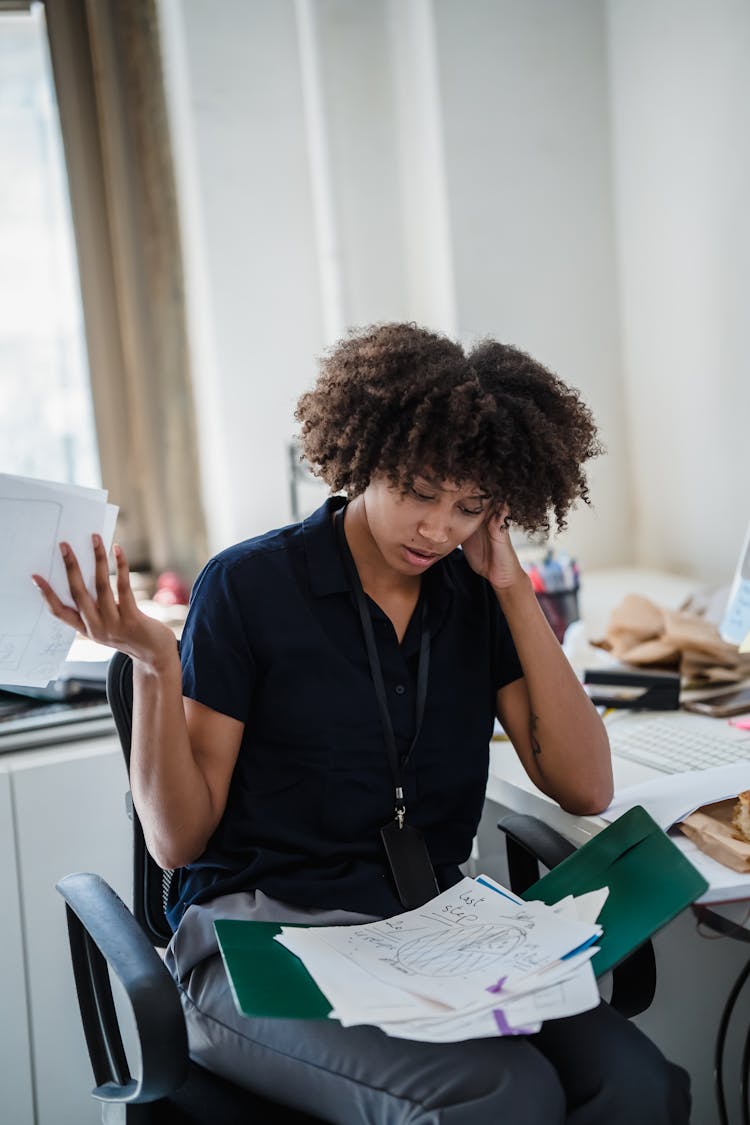 Woman Looking Through Documents And Making A Confused Facial Expression 