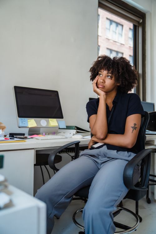 Free Young woman deep in thought at a modern office desk. Ideal for themes of work and creativity. Stock Photo