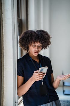 A woman with curly hair gesturing emotionally while engaged in a phone call indoors.