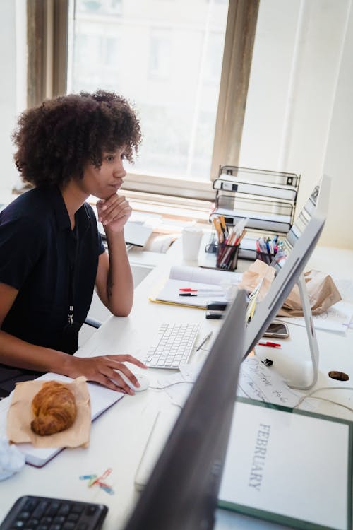 Woman Working on a Computer with on a Croissant her Desk 