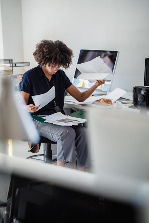 Free Woman in an Office Looking Through Documents on her Lap Stock Photo
