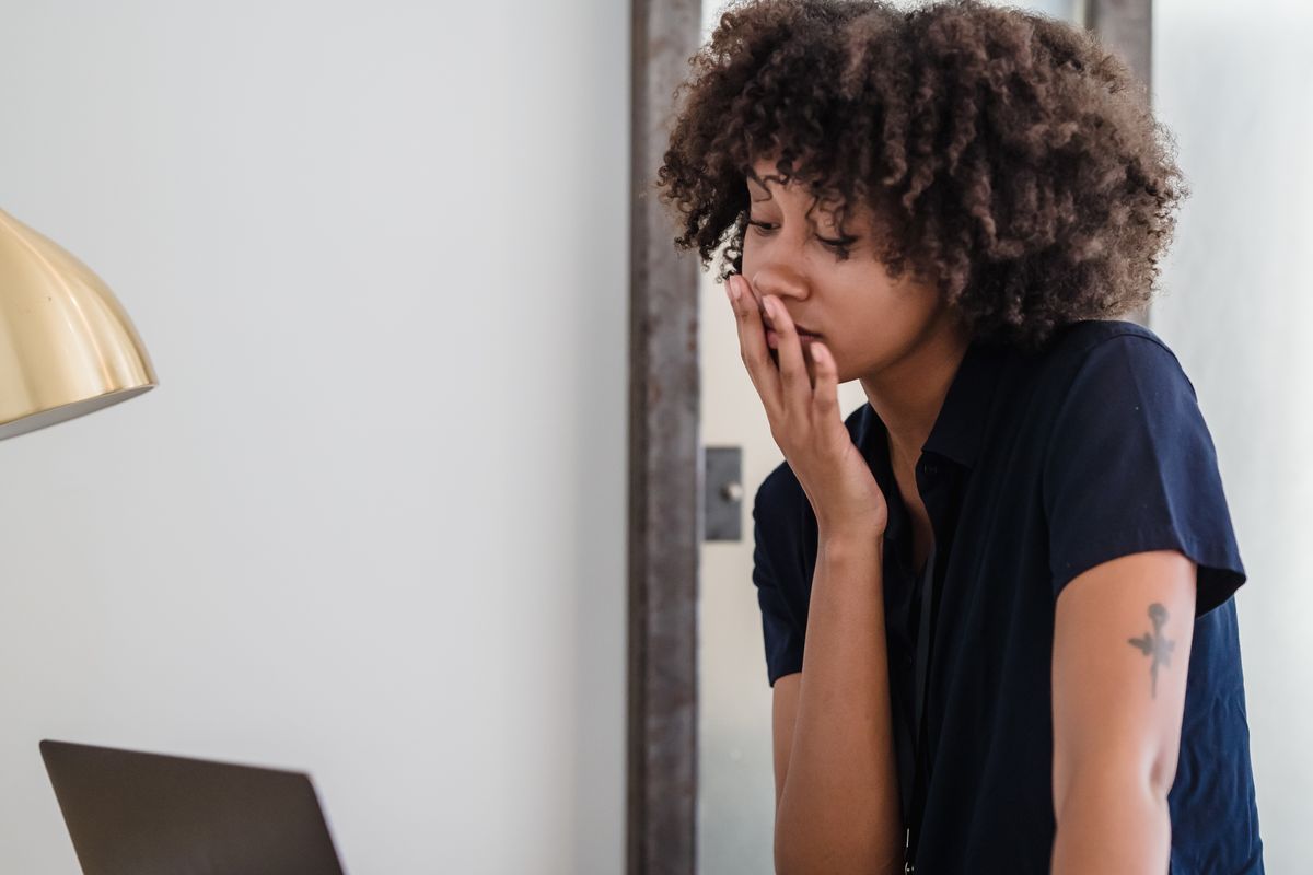 Malaysian woman yawning at a work desk in the afternoon