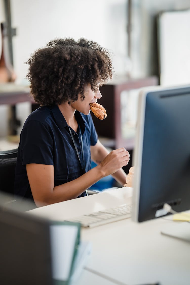 Woman Eating Pastry At Work