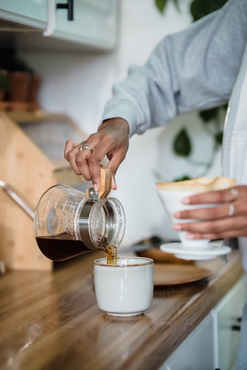 Close-up of Woman Pouring Coffee from a Coffee Pot into a Cup 