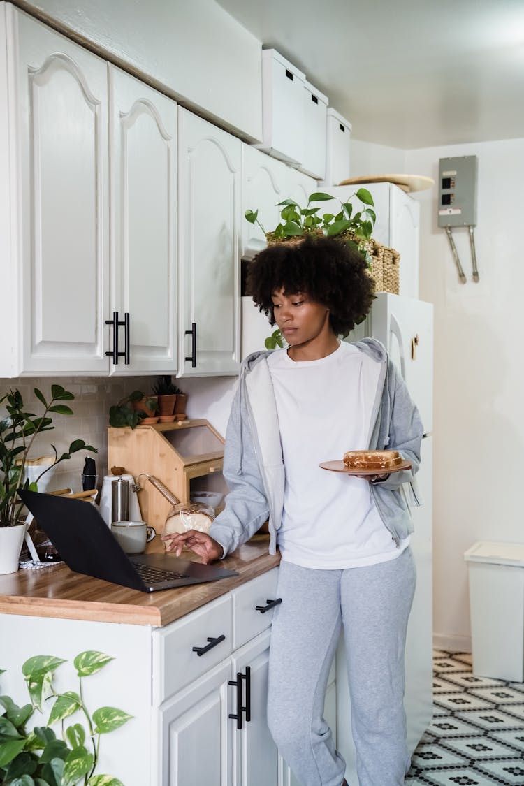 Woman Making Breakfast And Using Laptop In The Kitchen 