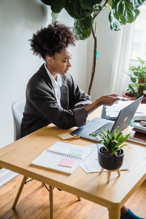 Free African American businesswoman engaged in remote work, using a laptop at a home office desk. Stock Photo
