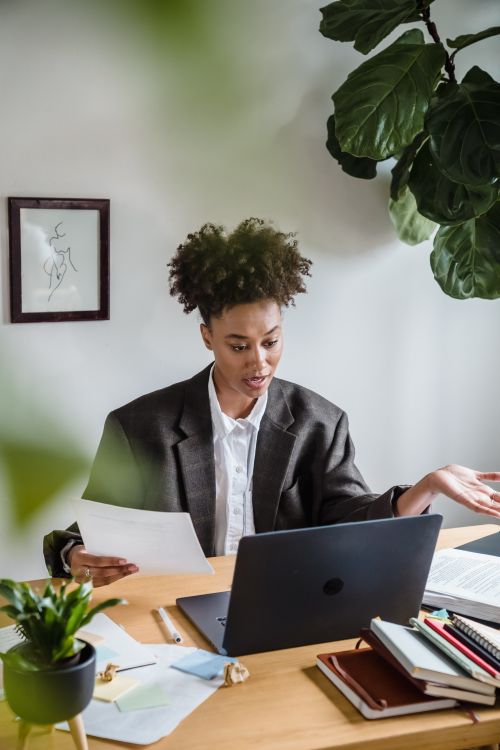 Free Young woman engaged in remote work video call from a stylish home office desk. Stock Photo