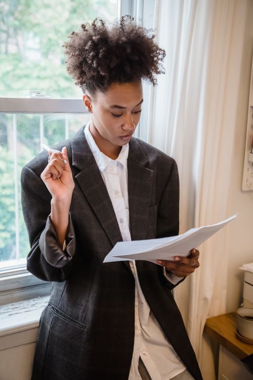 Free Young adult reviewing papers in a home setting, embodying focus and concentration. Stock Photo