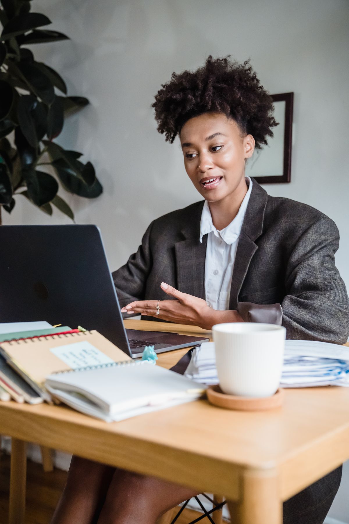 Professional woman on a video call, working remotely from home office with a laptop. Illustrative editorial photograph.