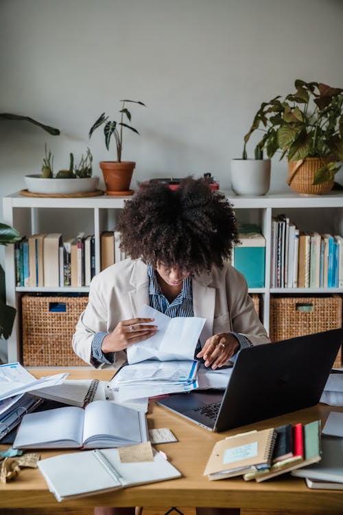 Woman Sitting Behind a Desk and Looking Through Papers 