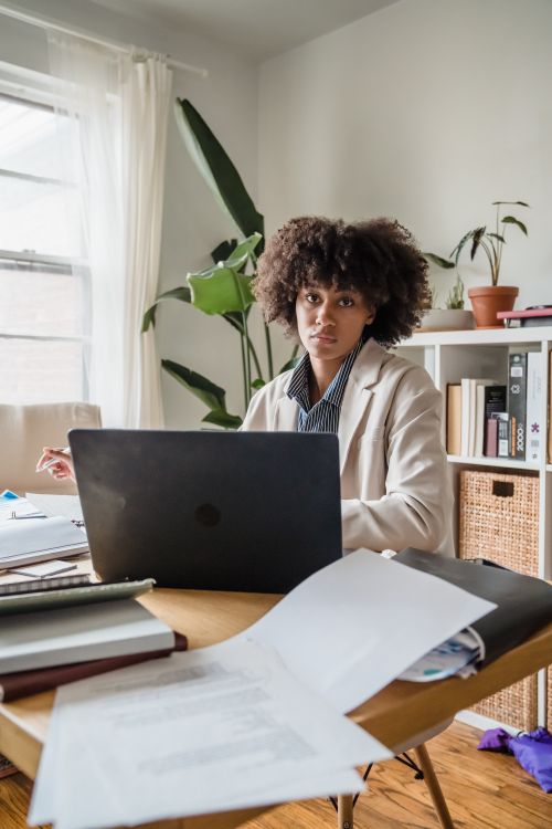 Free Young woman working in a home office setting with a laptop and documents. Stock Photo