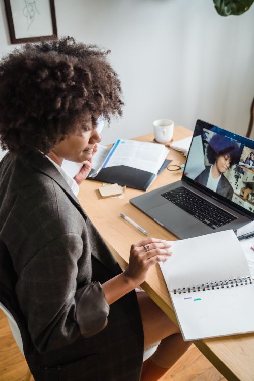 A professional taking notes during an online discussion