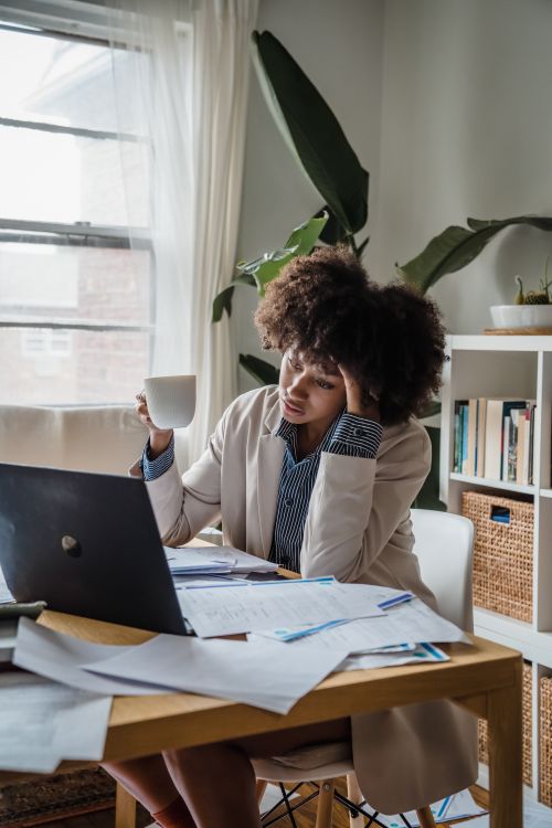 Free Woman in home office stressed while working remotely on laptop with coffee Stock Photo