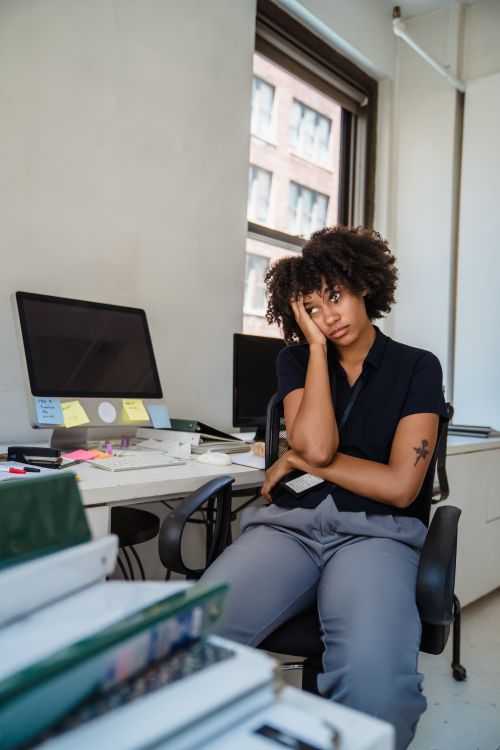 Free A tired woman sitting at her desk, feeling stressed in a modern office environment. Stock Photo
