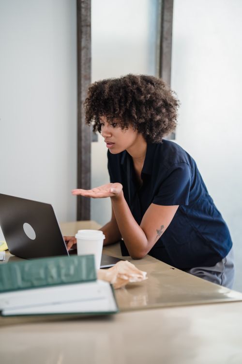 Free Focused woman participates in a remote work video call using a laptop in her home office. Stock Photo