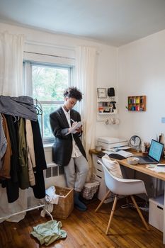Adult standing by window in a home office, taking notes during a work-from-home session.
