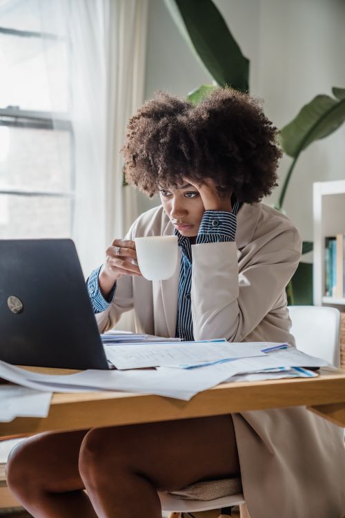 Free Woman working at desk with laptop and coffee cup, focusing on tasks. Stock Photo