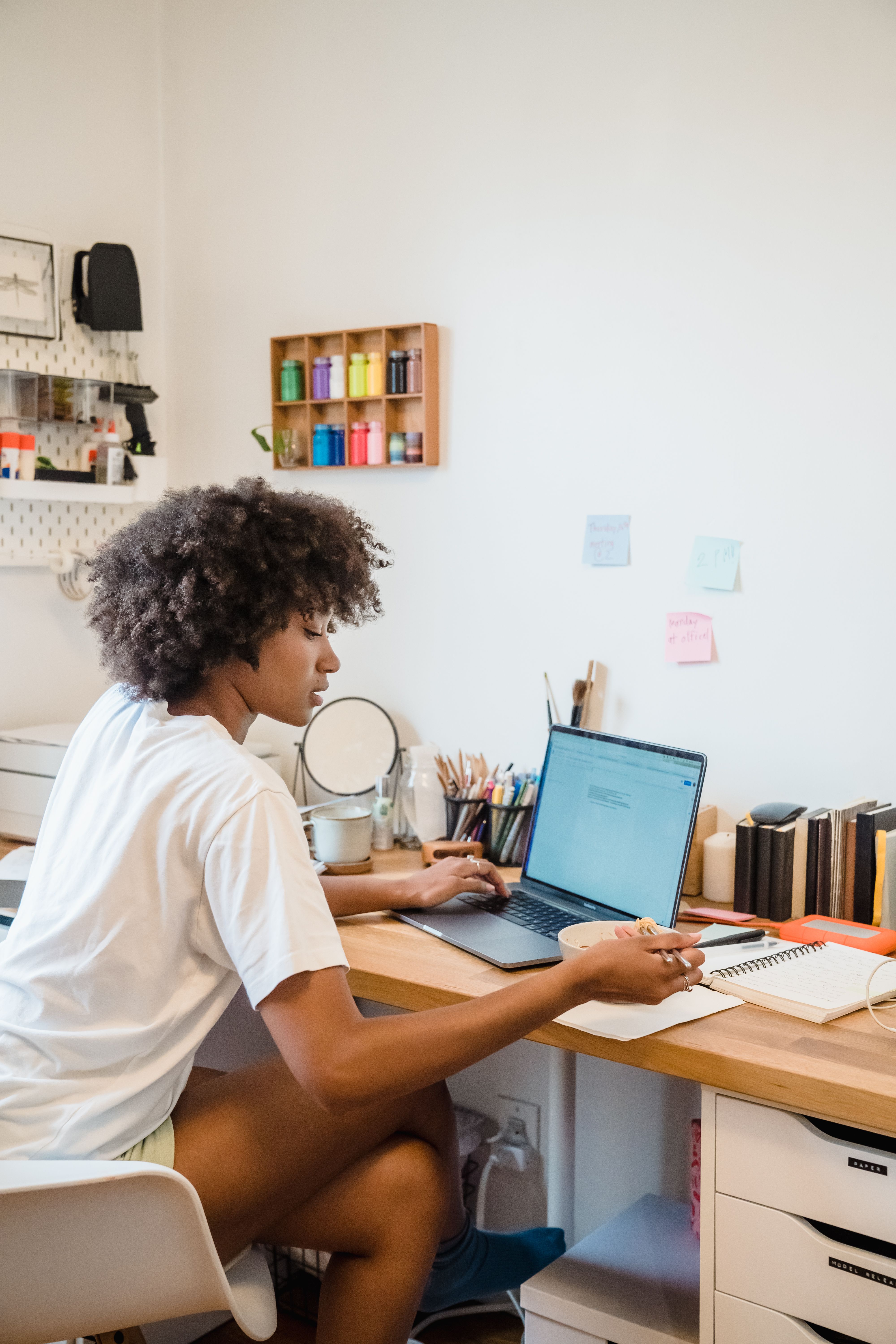 A student holding a hot beverage while reviewing a weekly schedule on a laptop