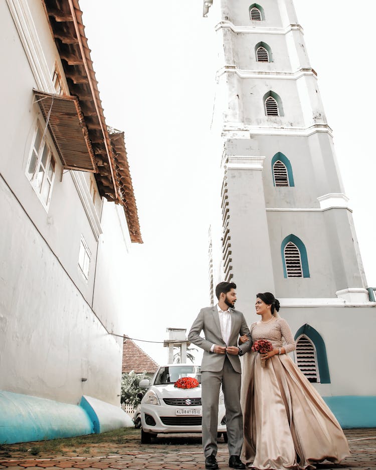 Low-Angle Shot Of A Romantic Wedding Couple Standing Near Church Tower