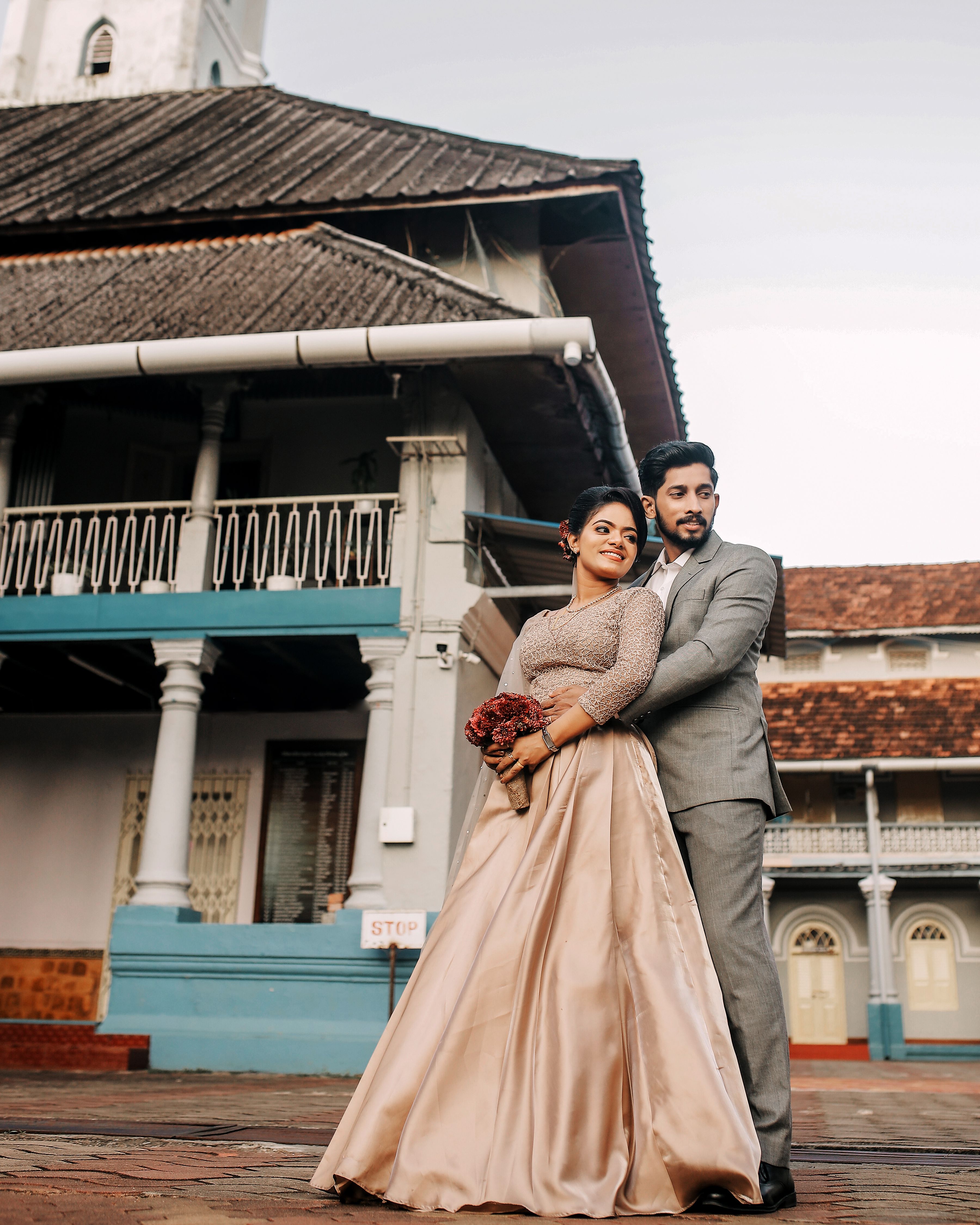 A romantic wedding couple stand in front of traditional architecture, embracing their love.