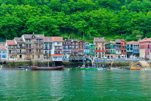 Free Explore the vibrant coastal town with colorful buildings and boats in PV, Spain along lush green hills. Stock Photo