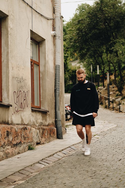 Man in Black Crew Neck Sweater and Black Shorts Standing on Gray Concrete Pavement