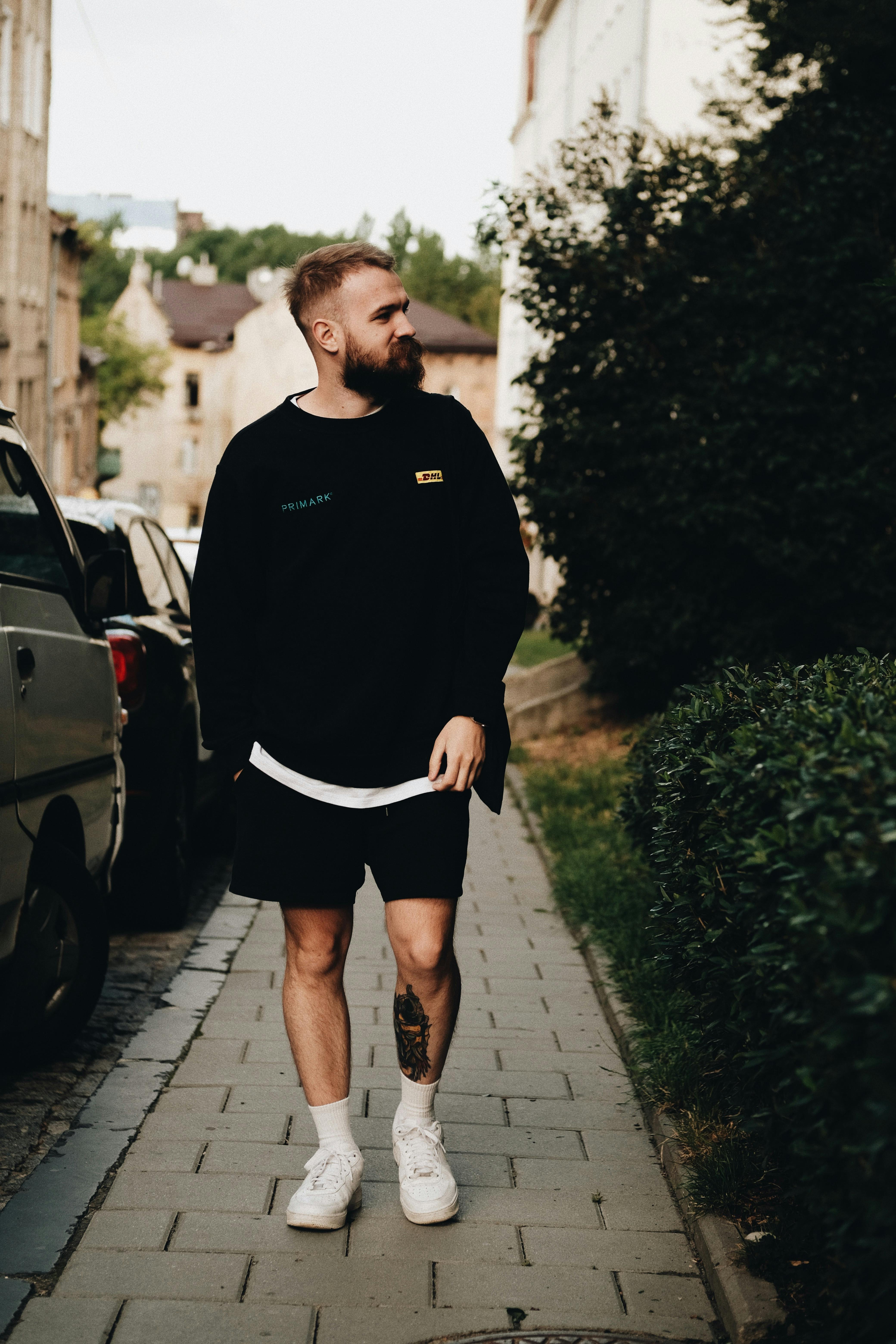 Casual portrait of a bearded man walking artistically on a city street. Ideal for fashion and lifestyle themes.