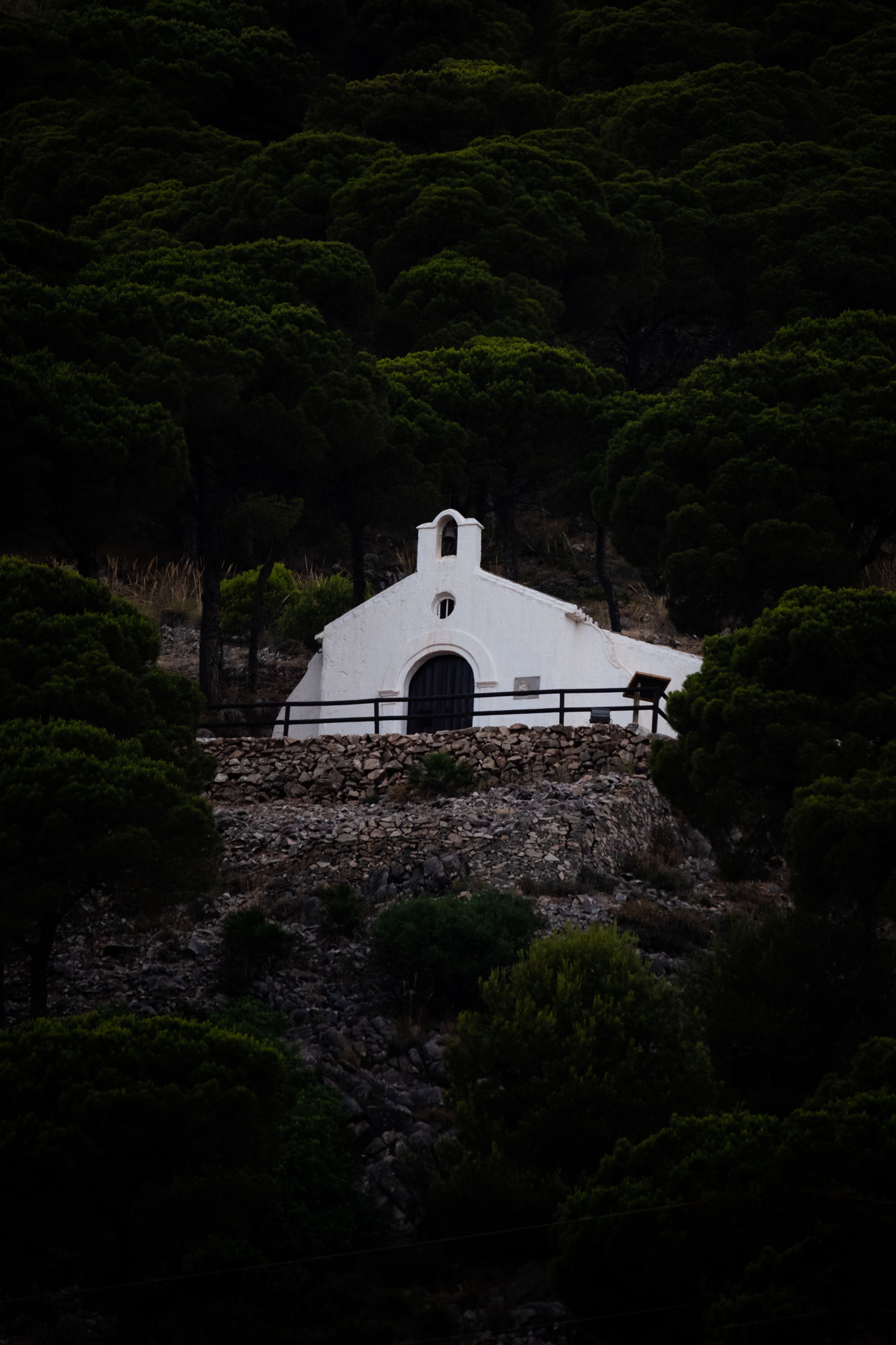 White hermitage nestled in lush green forest of Mijas, Spain, offering a tranquil retreat.