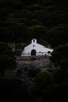 White hermitage nestled in lush green forest of Mijas, Spain, offering a tranquil retreat.