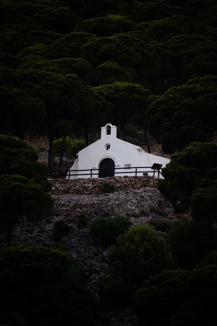 White hermitage nestled in lush green forest of Mijas, Spain, offering a tranquil retreat.