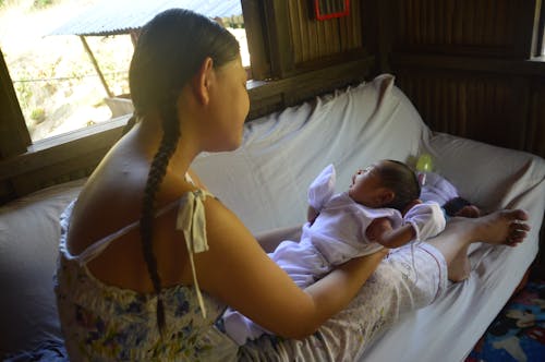 Woman Carrying Her Baby while Sitting on the Couch