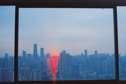 City skyline seen through a window at dusk, by 1ndex on Pexels