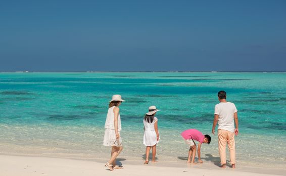 A family of four enjoying a relaxing day on a pristine sandy beach with turquoise ocean waves.